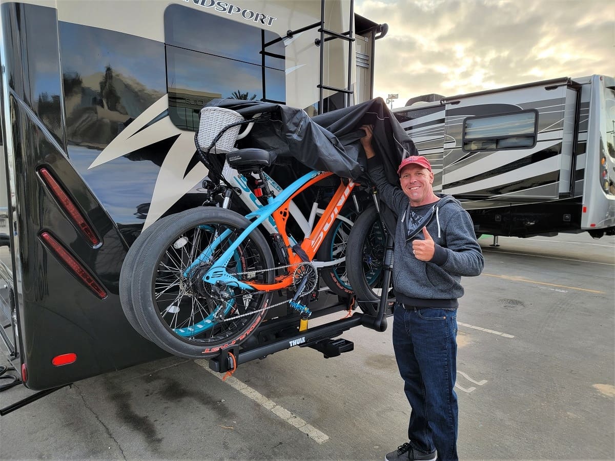 Man with bikes on RV bike rack.