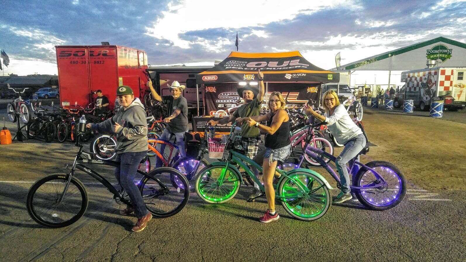 Group posing on colorful bicycles at event.