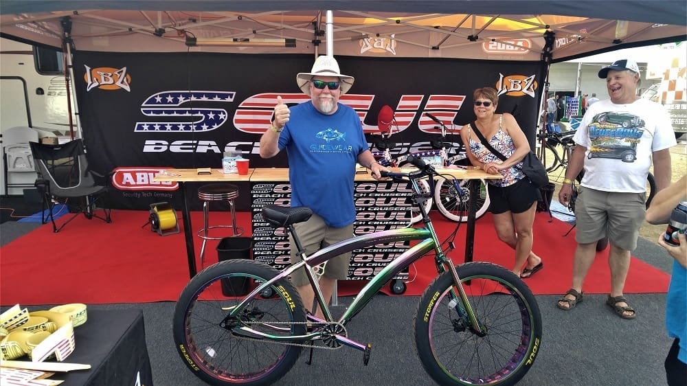 Man posing with a bicycle at booth.