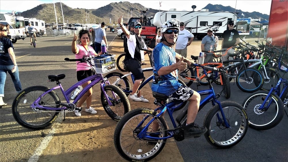 Group of cyclists posing with bicycles outdoors.