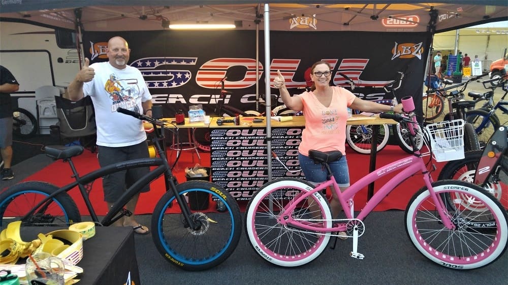 Two people posing with colorful bicycles.