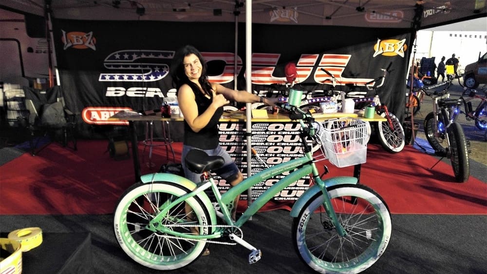 Woman posing with a teal bicycle.