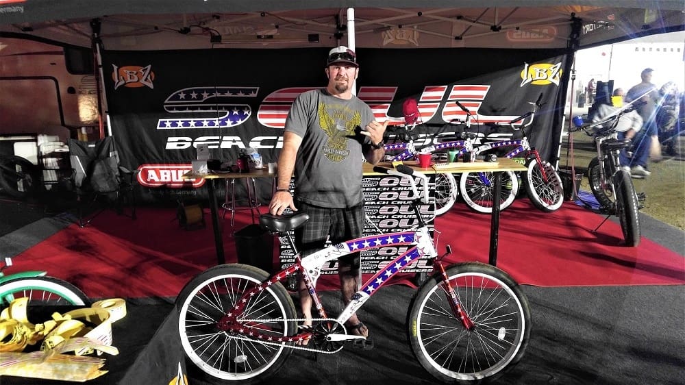 Man posing with bike at a booth.