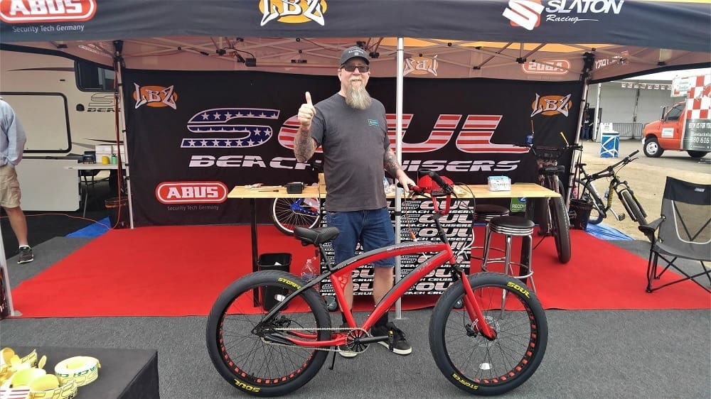 Man giving thumbs up with red bicycle.
