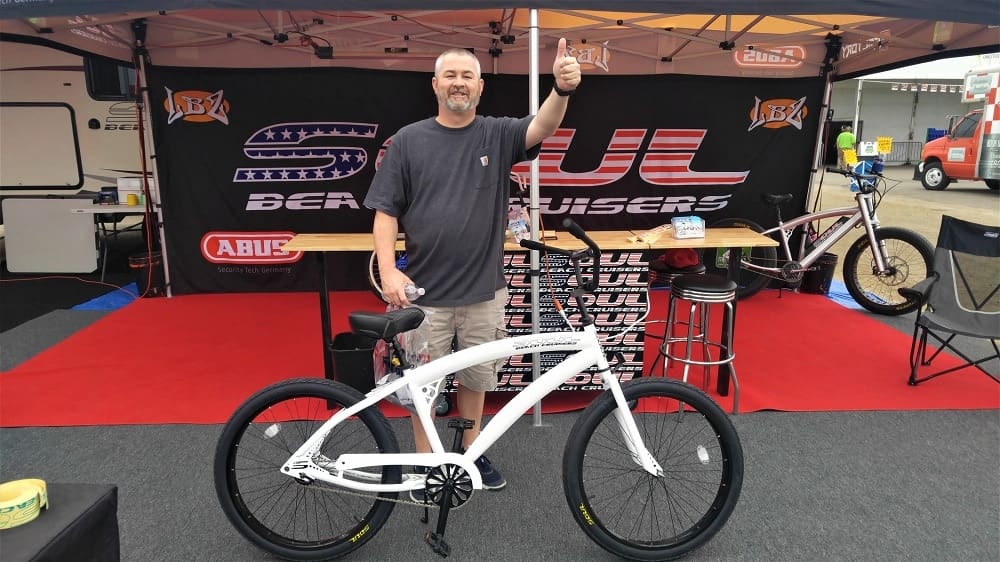 Man giving thumbs up with white bicycle.