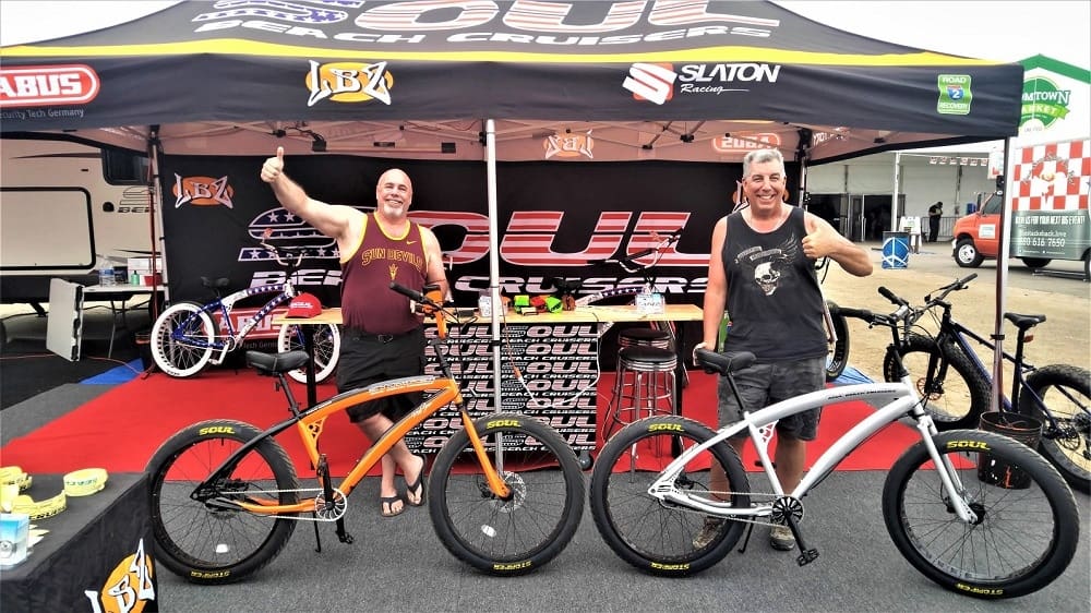 Two men with bikes at outdoor booth.