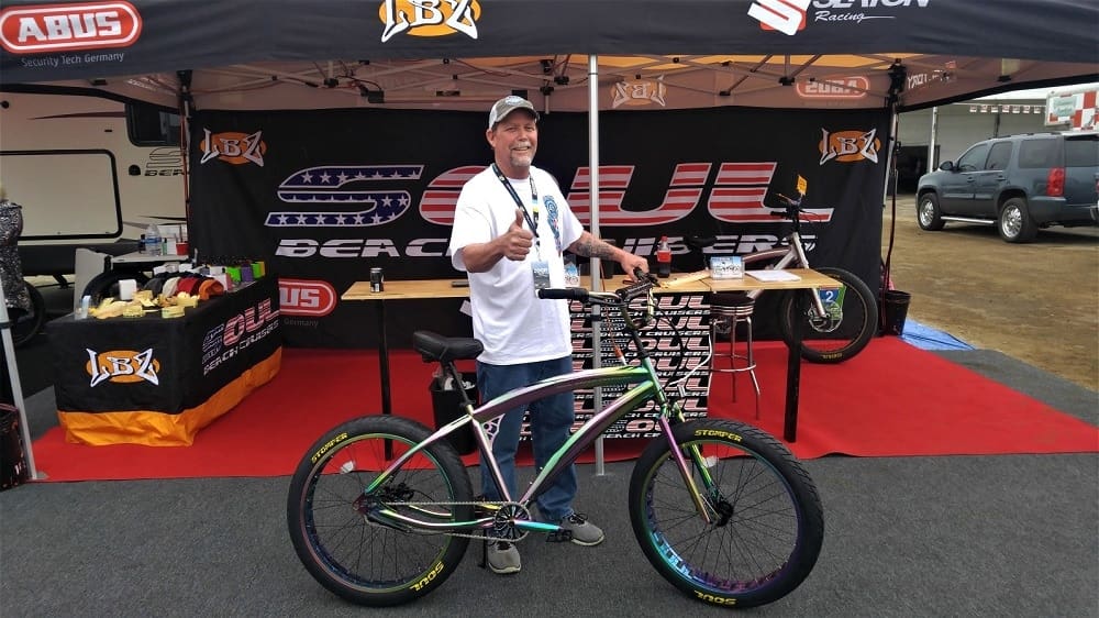 Man posing with colorful bike at event.