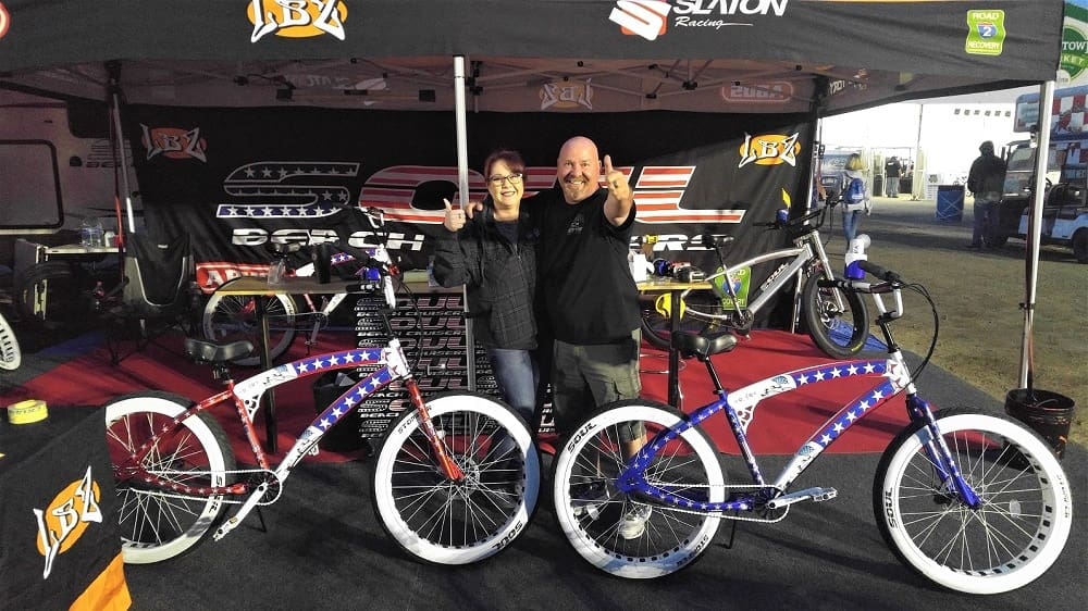 Two people posing with patriotic-themed bicycles.