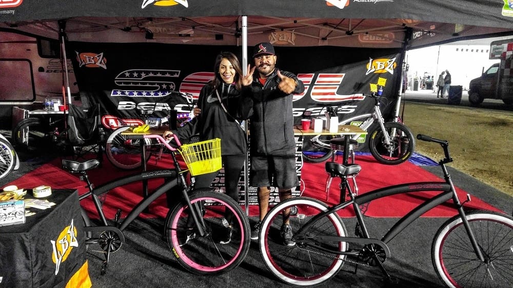 People posing with custom bicycles at event.