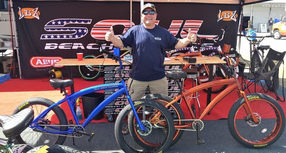 Man posing with two colorful bicycles.