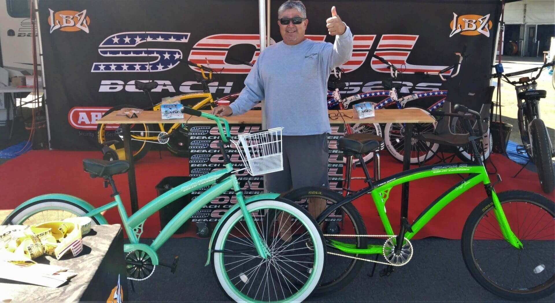 Man posing with bicycles at a booth.