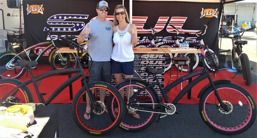 Couple posing with custom bicycles at event.