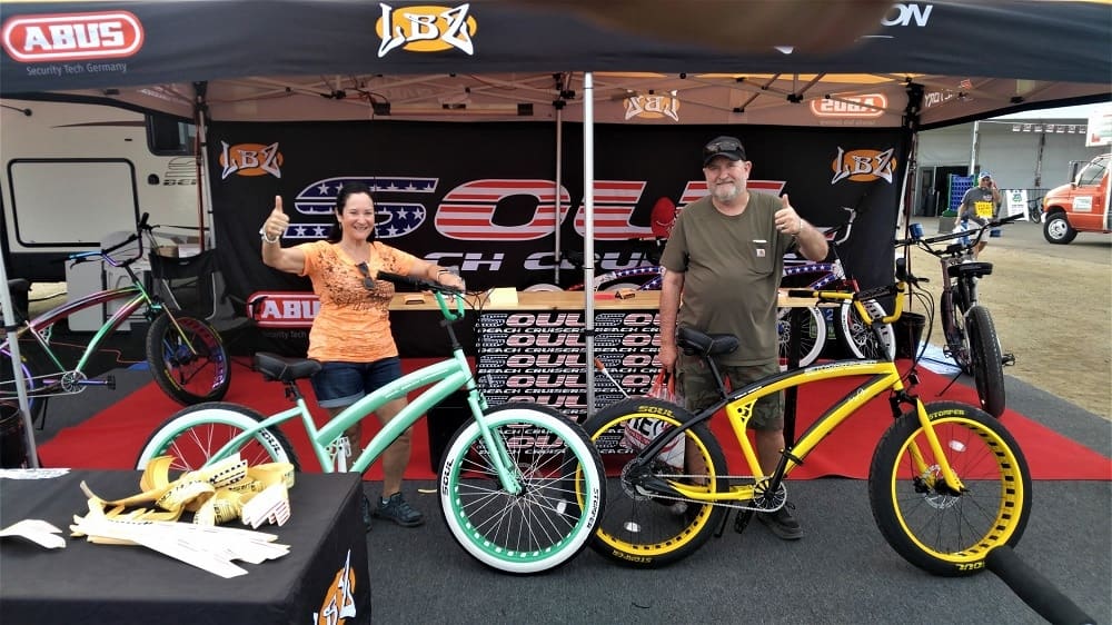 Two people with bicycles at outdoor booth.