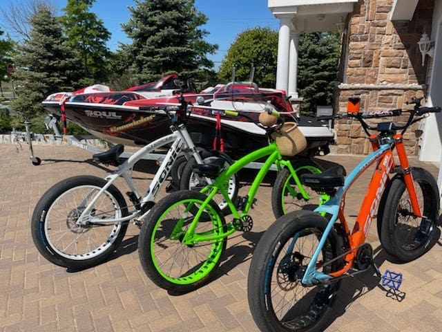 Bicycles and boat parked on brick driveway.