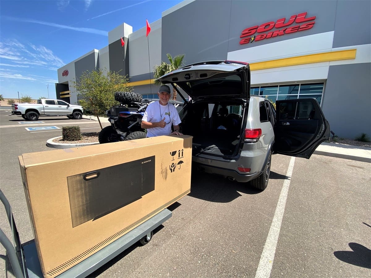 Man loading large box into SUV.