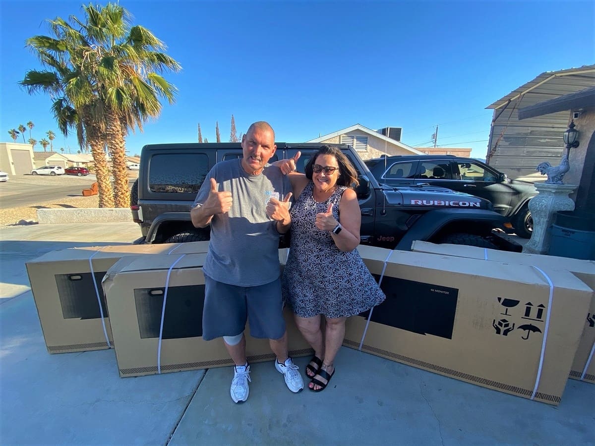 Couple smiling with large boxes outdoors.