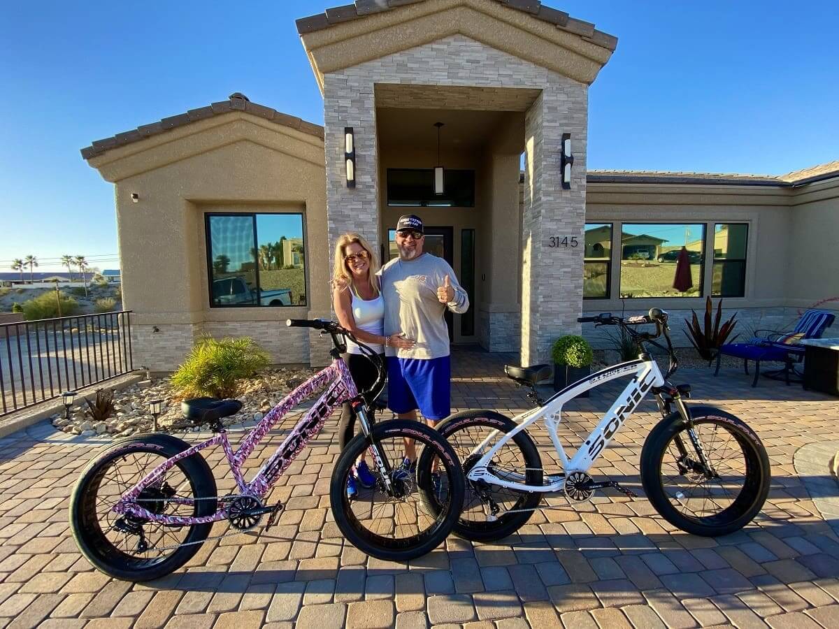 Couple with bikes in front of house.