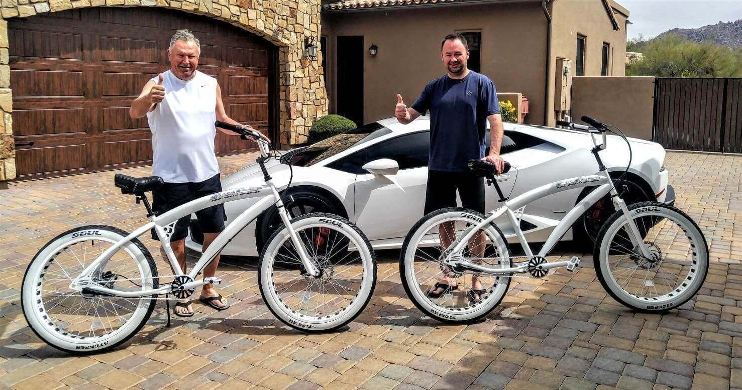 Two men with bicycles near luxury car.