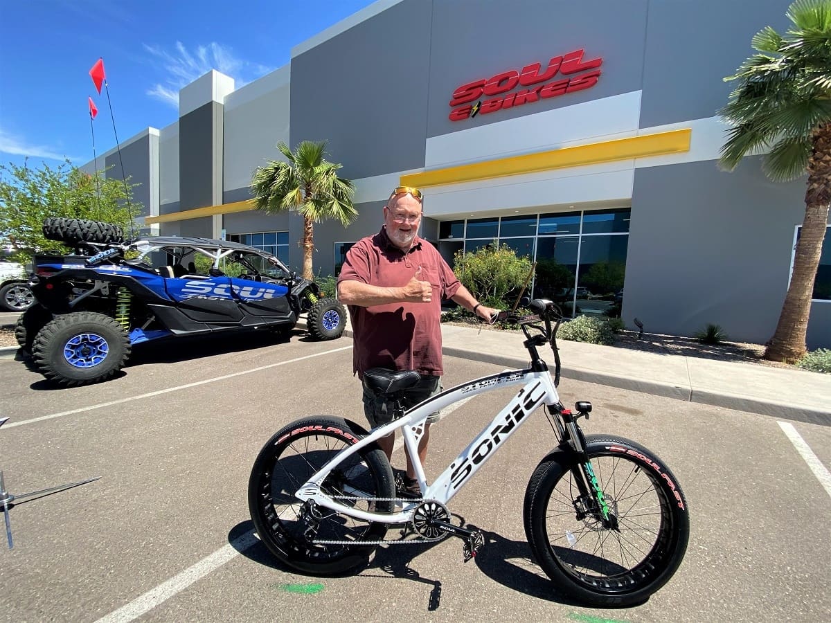 Man with bike in front of store.