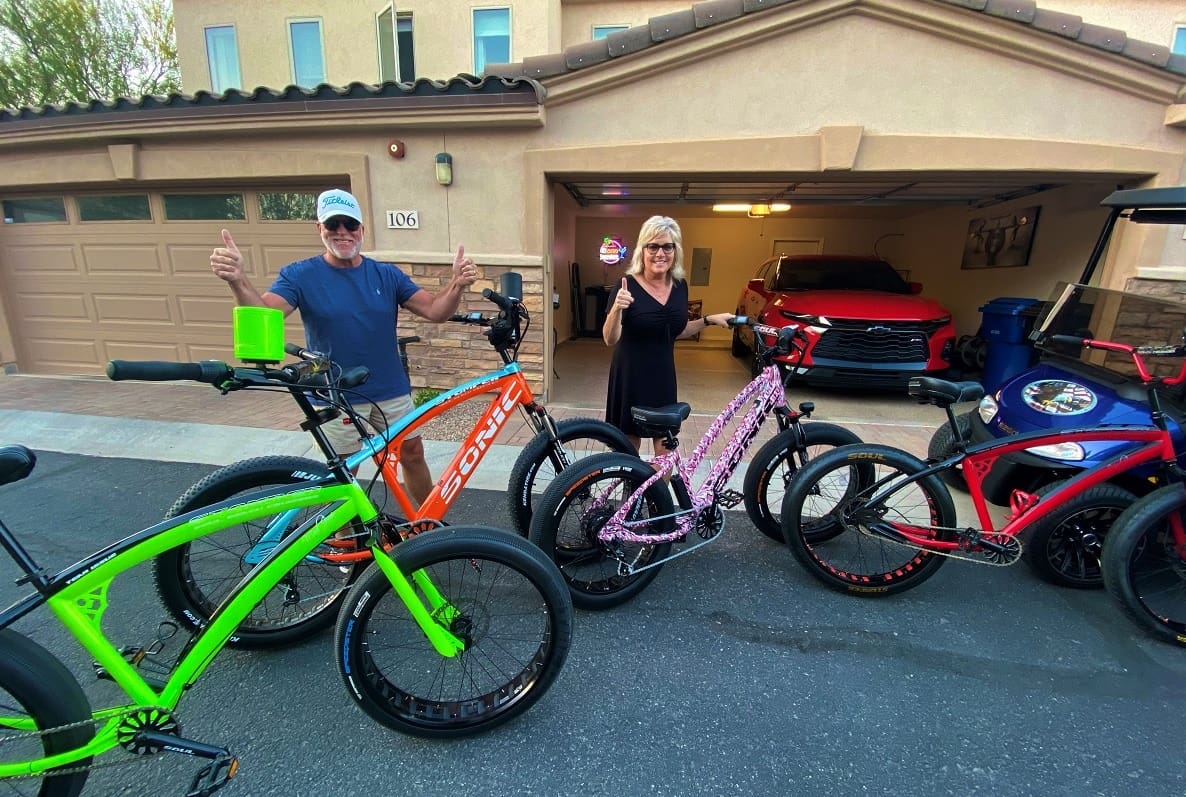 People with colorful bicycles in driveway.