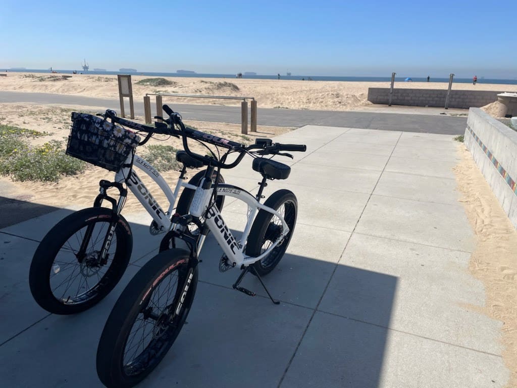 Two bicycles parked near a sandy beach.