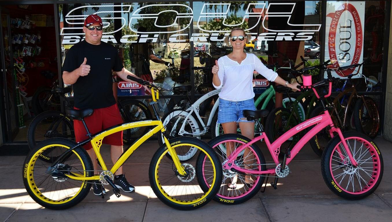 Two people with colorful beach cruiser bicycles.