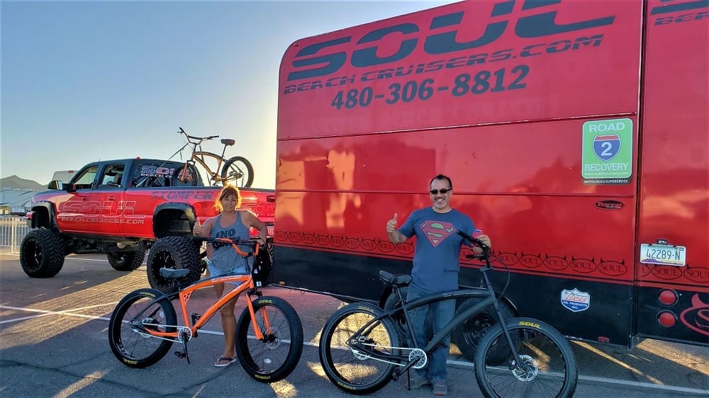 Two people with bikes beside red van.