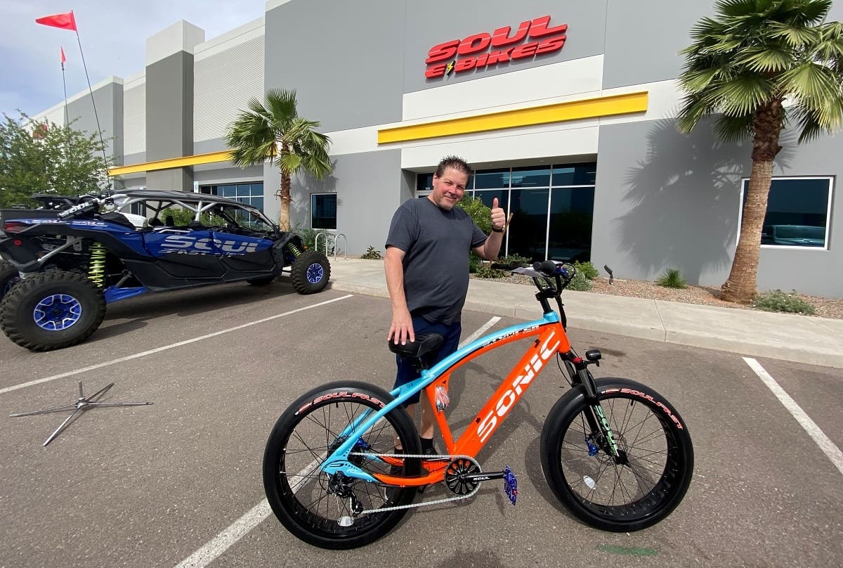 Man giving thumbs up beside colorful bicycle.