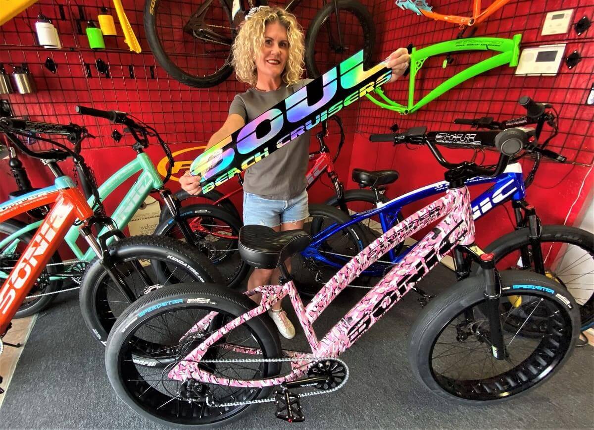 Woman holding colorful bicycle frame in shop.