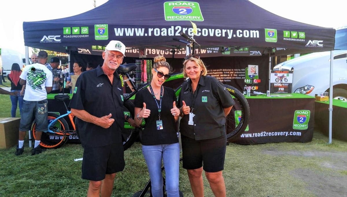 Three people posing at Road2Recovery booth.
