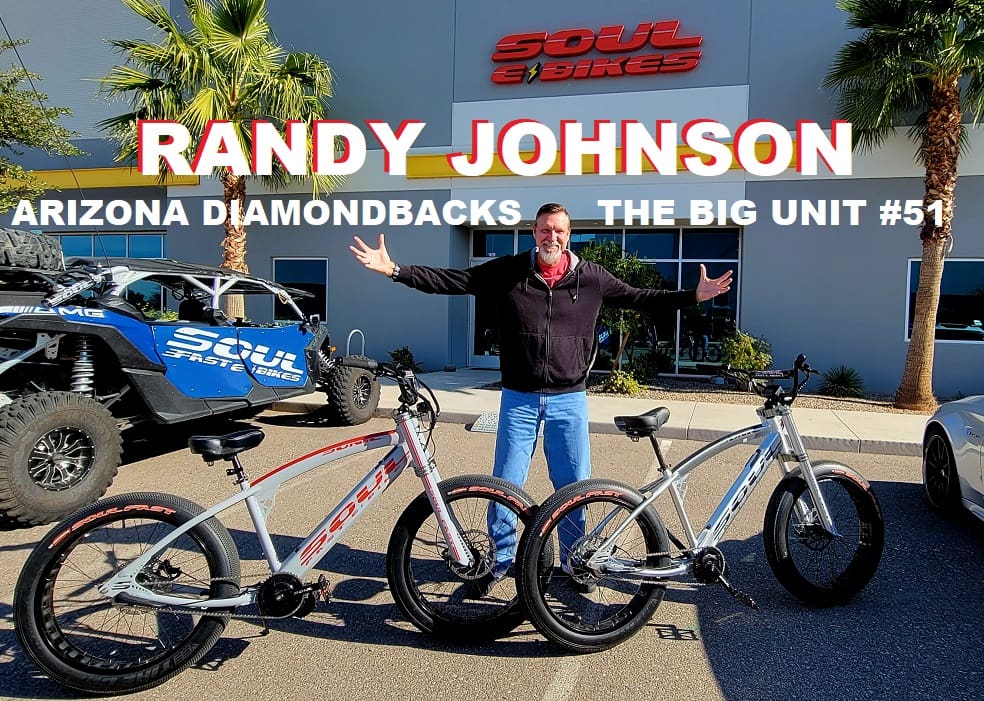 Person posing with three electric bikes outside store