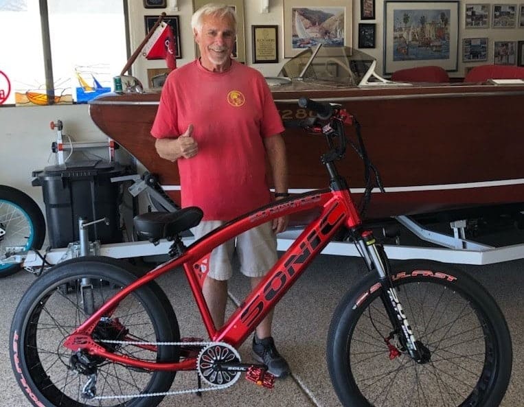 Man with red bicycle in garage.