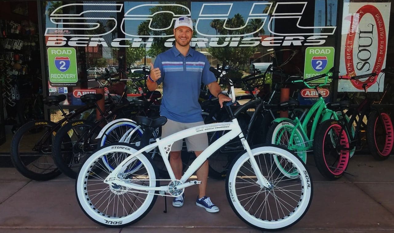 Man standing with white beach cruiser bike.