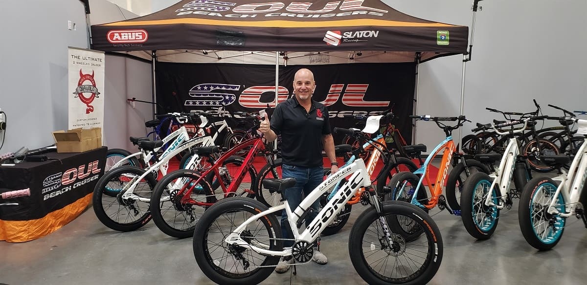 Man standing with bicycles at exhibition booth.
