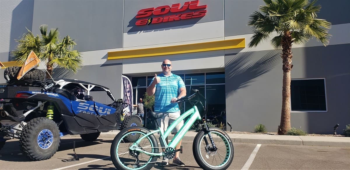 Man with bicycle outside Soul e Bikes store.