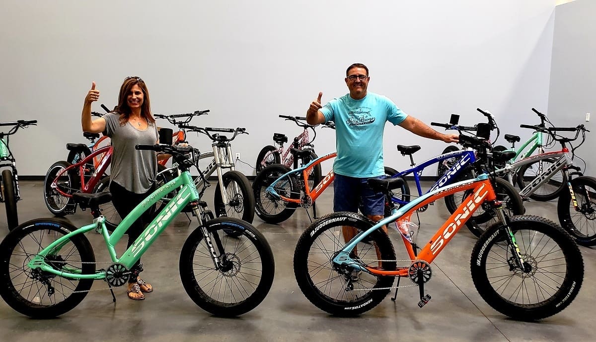Two people giving thumbs up with bicycles.