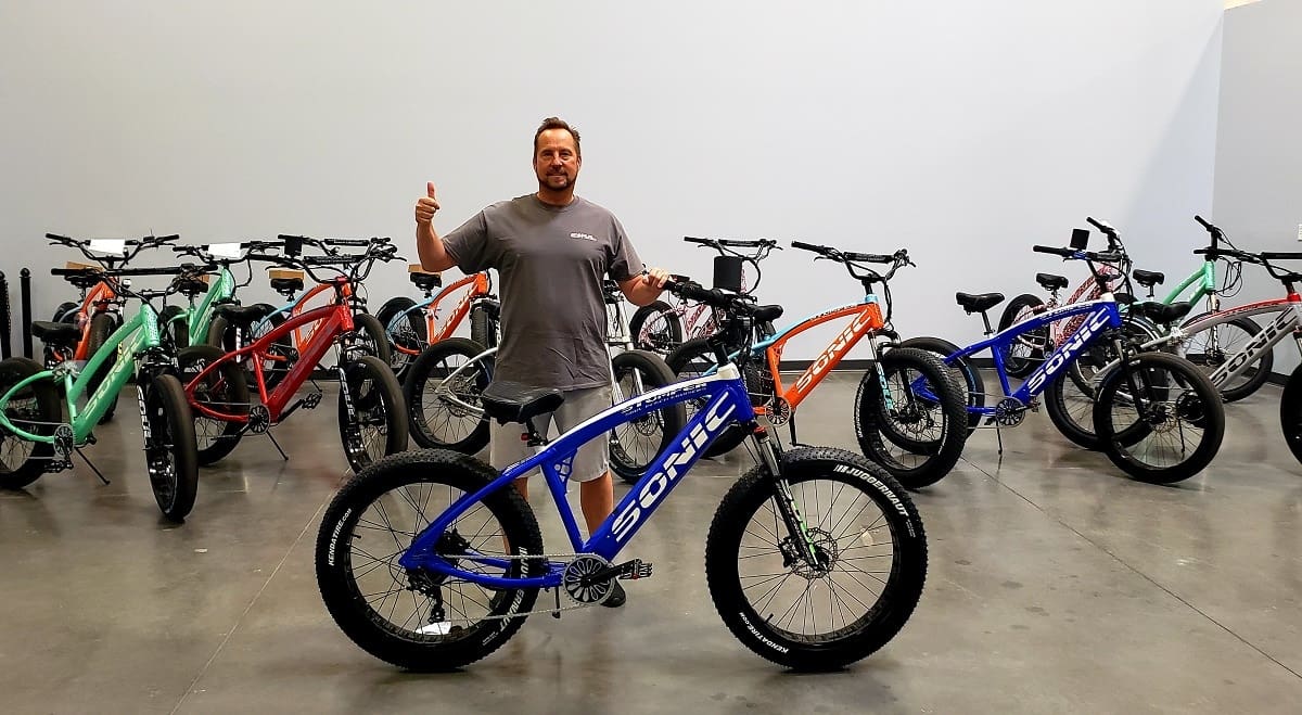 Man standing with multiple colorful bikes.