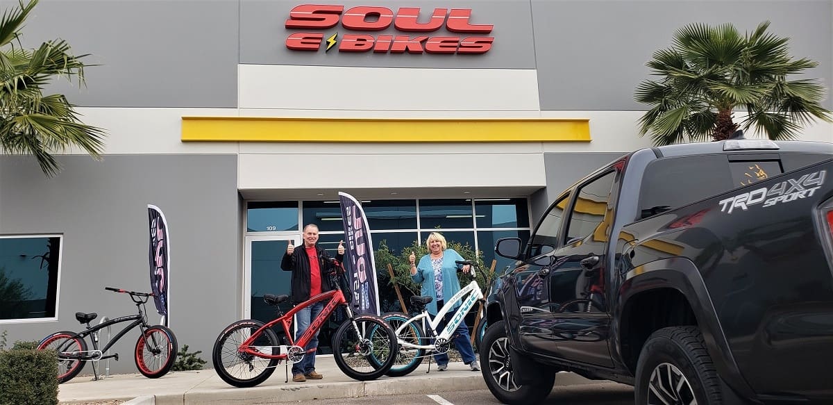 People with bikes in front of store.