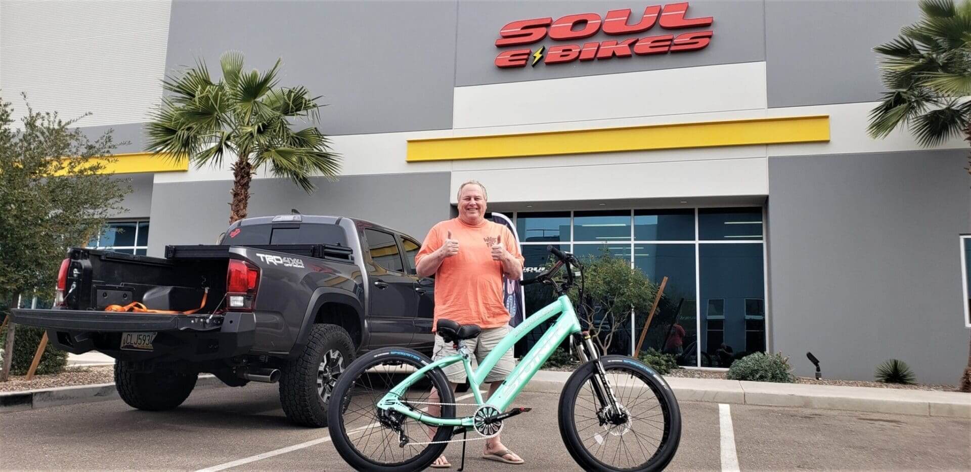 Person with bicycle outside Soul E Bikes shop.