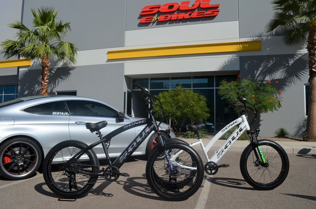 Two bicycles near a car and building.
