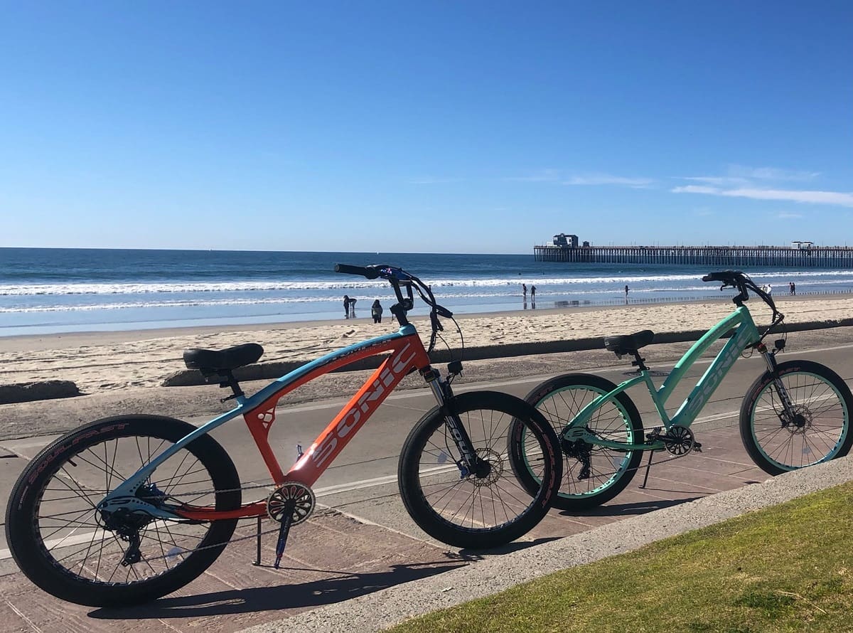 Bicycles parked by the beach and pier.