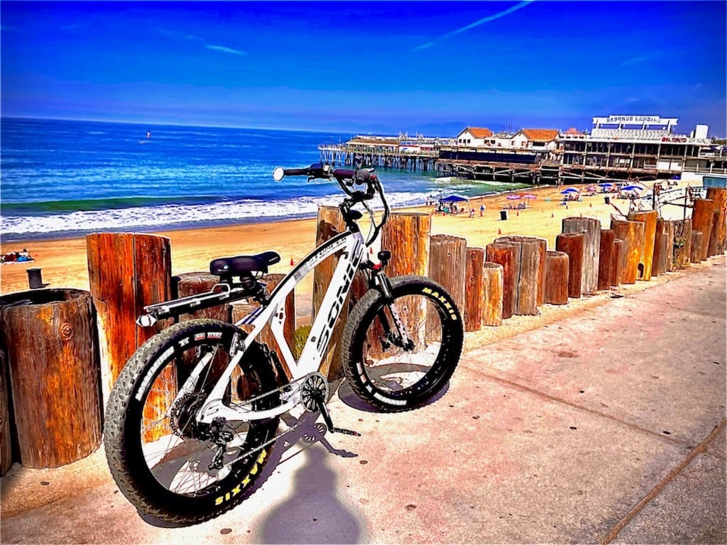 Bicycle parked by oceanfront boardwalk and beach.