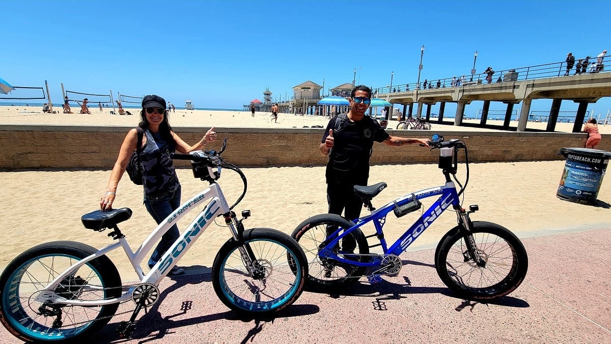 Two people with bikes at the beach.