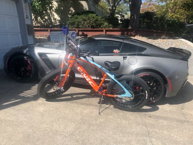 Bicycle parked in front of sports car.