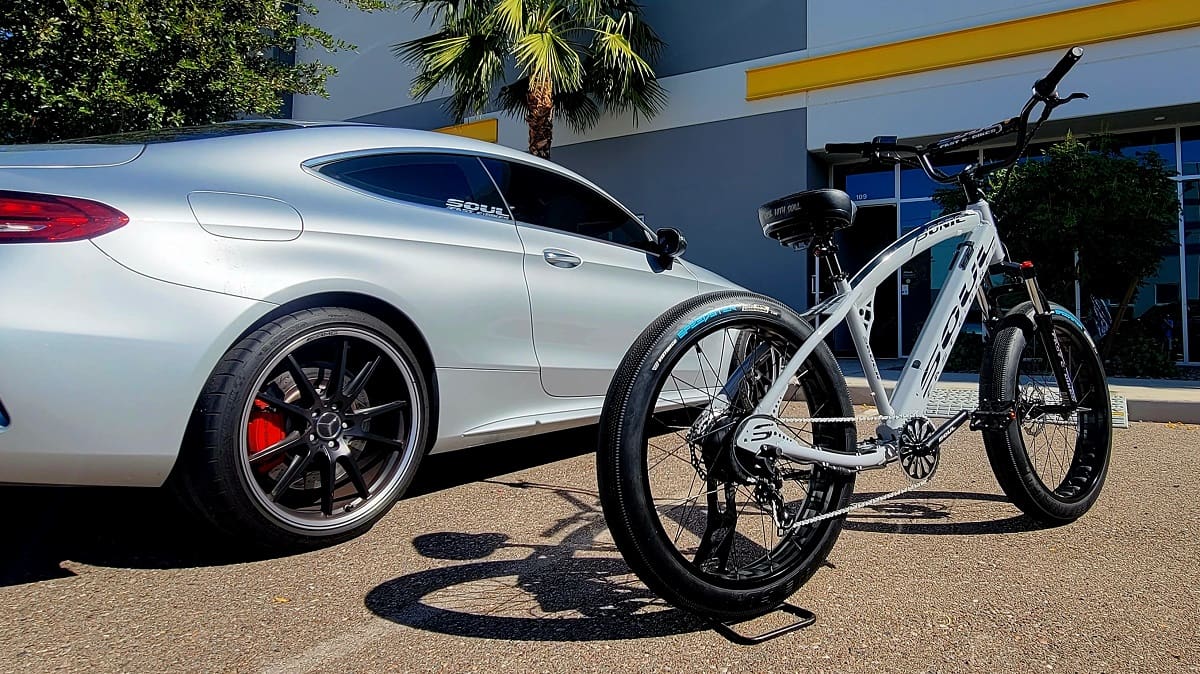 Silver car and white bicycle parked outside.