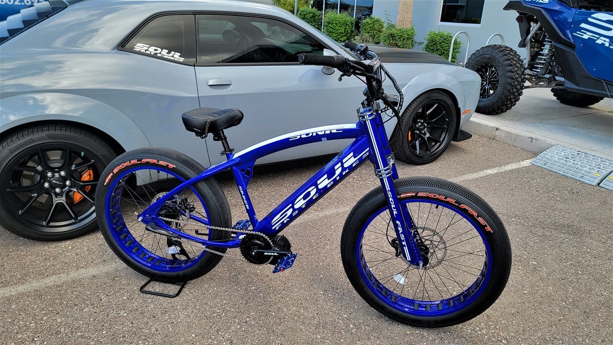 Blue bicycle parked next to gray car.