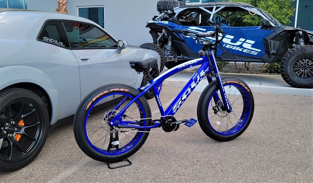 Blue bike beside car and off-road vehicle.