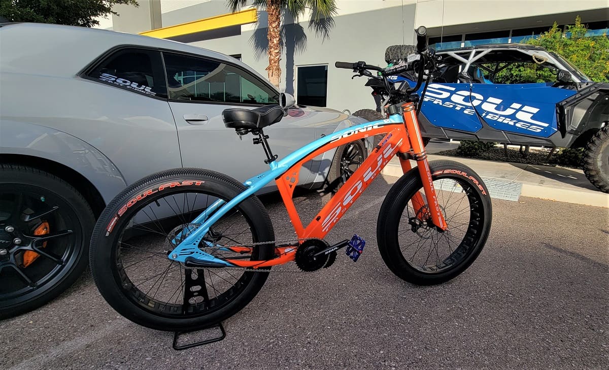 Electric bike parked between cars and ATV.