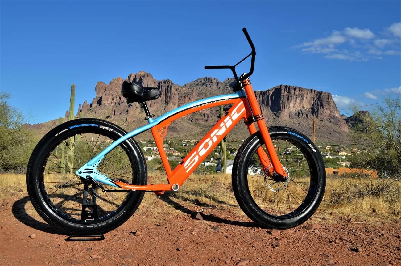 Orange bike in desert landscape with mountains.