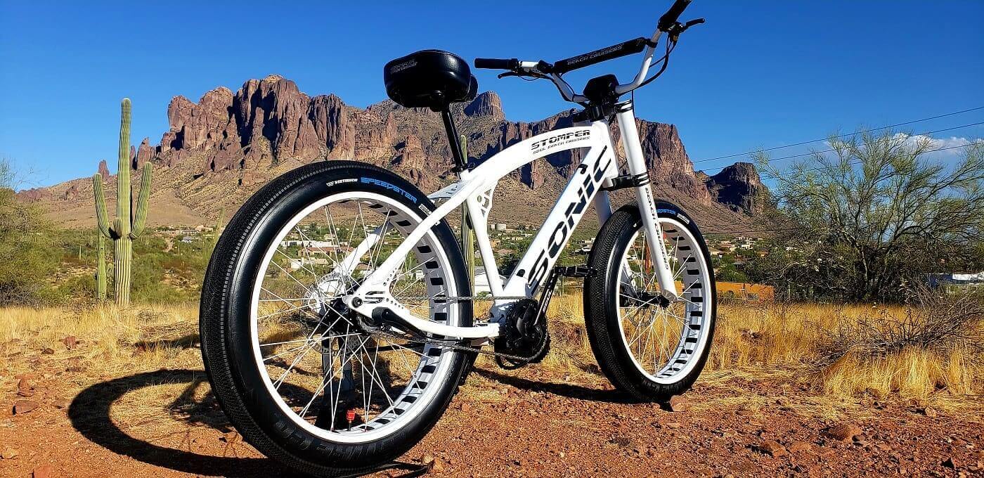 White bicycle in desert landscape with mountains.